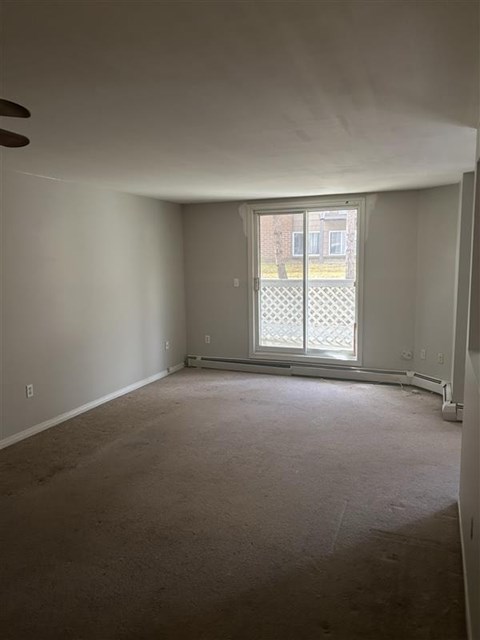 Empty room with a window and a fan on the ceiling.