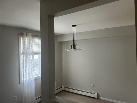 A room with a window and a hanging light fixture.
