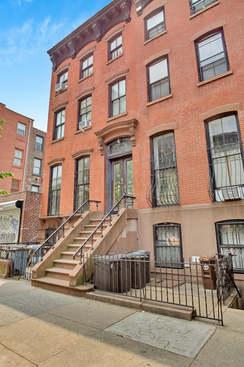A red brick building with a staircase leading to the front door.