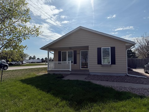 A small house with a porch and a white fence.