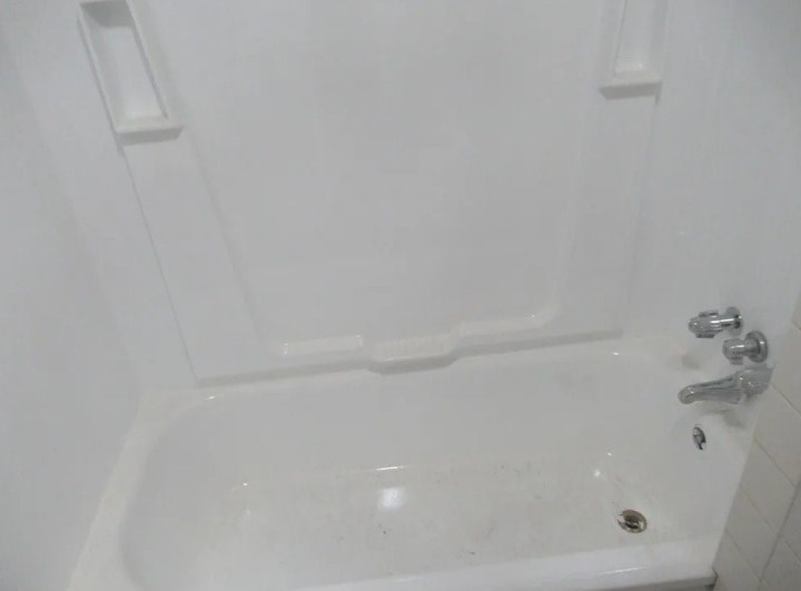 A white bathtub with a faucet and handles.