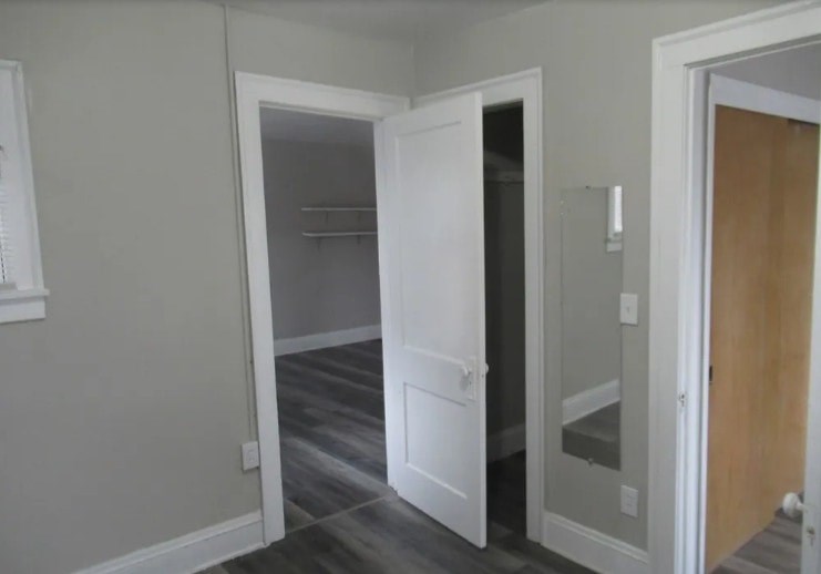 A white door is open to a room with a wooden floor.