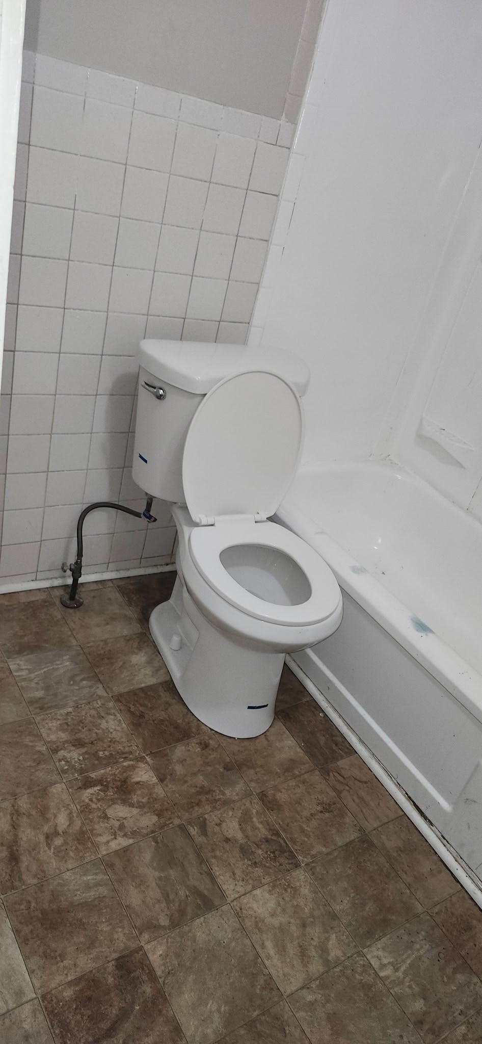 A white toilet with the seat up is in a bathroom.