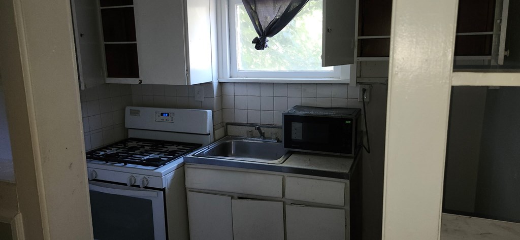 A small kitchen with a white oven and a microwave above a sink.