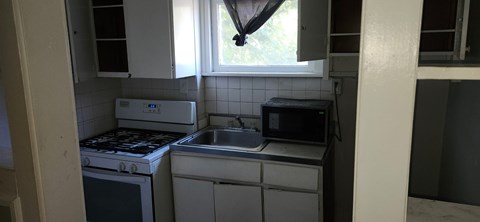 A small kitchen with a white oven and a microwave above a sink.