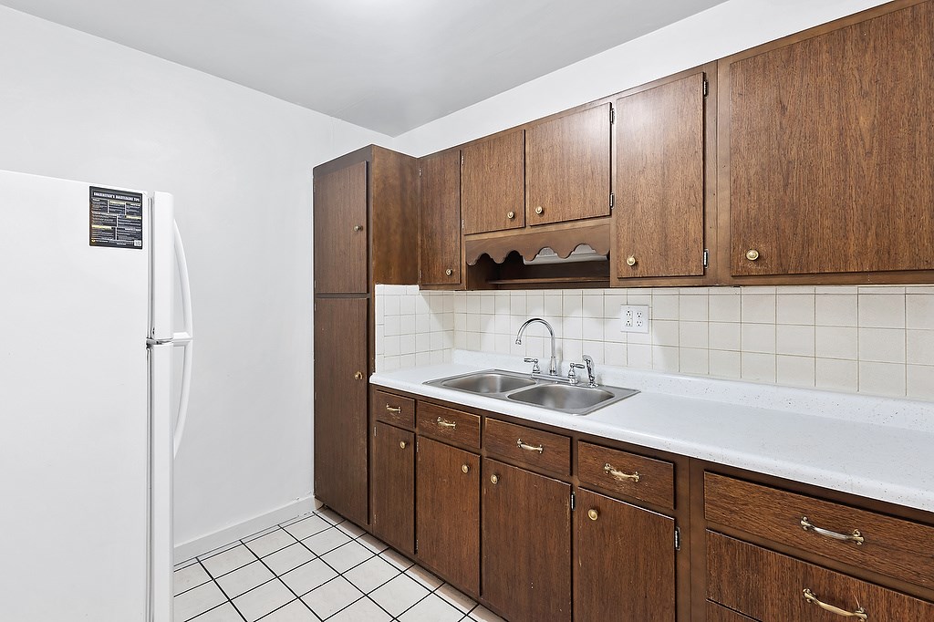A kitchen with brown cabinets and a white fridge.