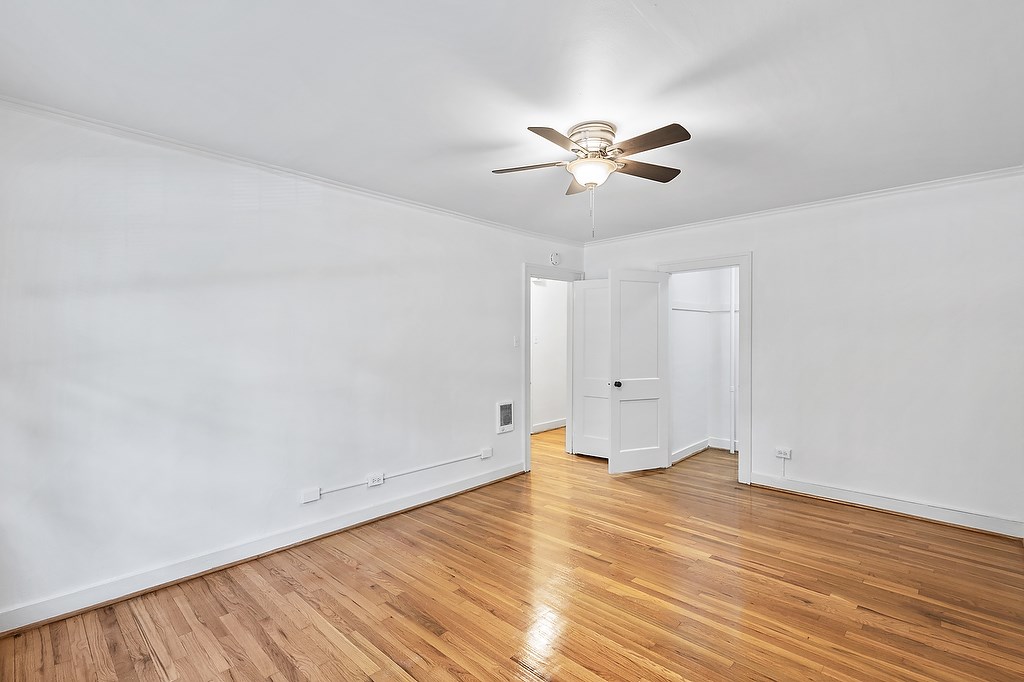 A room with a ceiling fan and wooden floors.