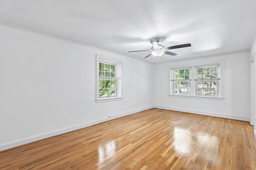 A room with a ceiling fan and two windows.