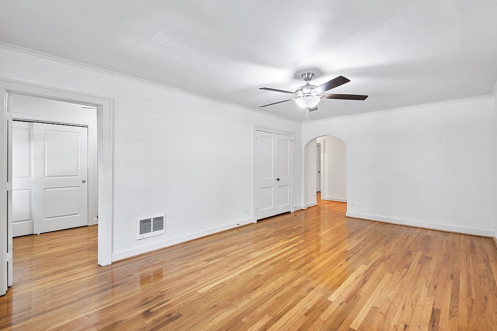 A room with a ceiling fan and wooden floors.
