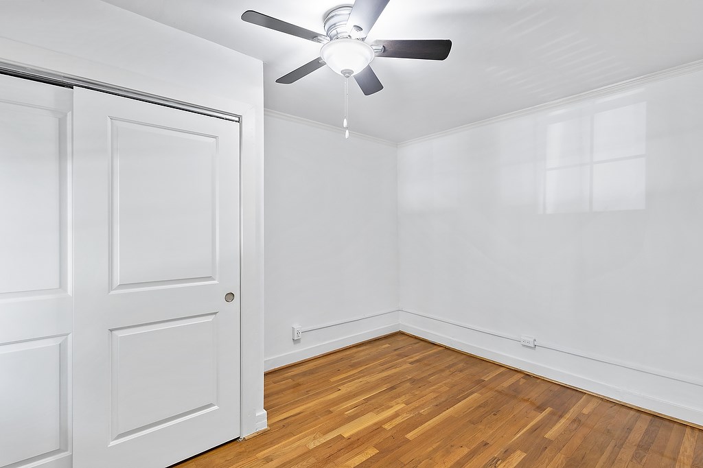 A room with a ceiling fan and a door.