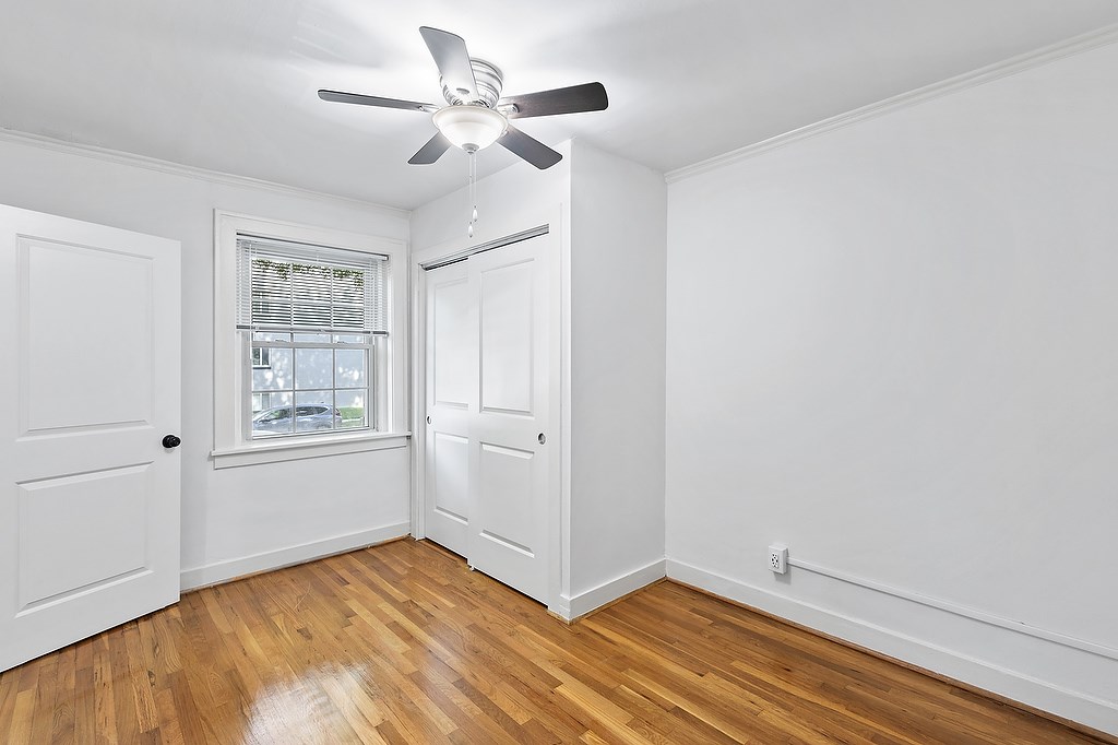 A room with a ceiling fan and a window with blinds.