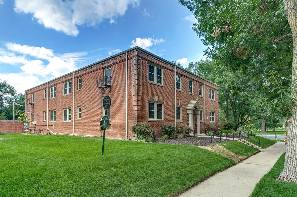 A red brick building with a green sign in front.