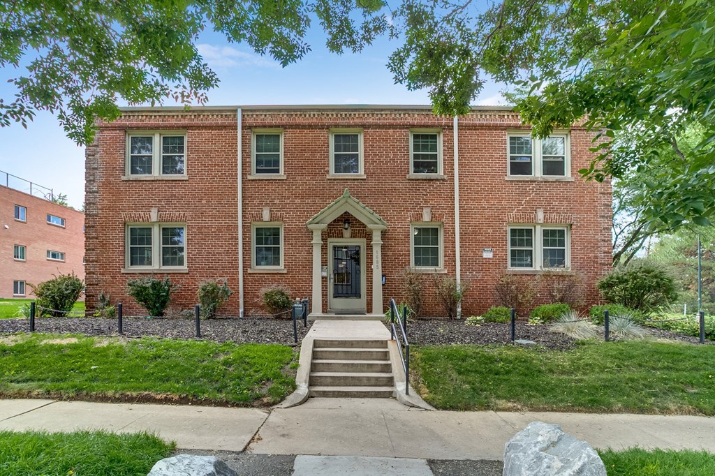 A red brick building with a black fence and a black gate.