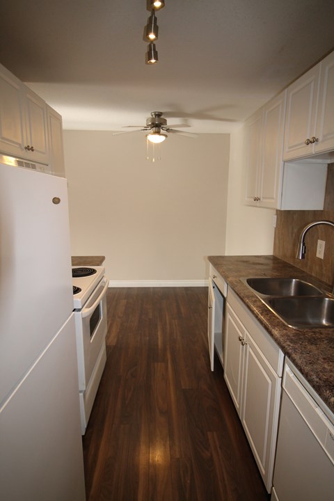A kitchen with a white refrigerator and wooden floors.