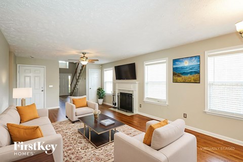 A living room with a fireplace and a painting of a beach scene on the wall.
