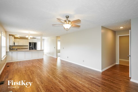 A spacious room with wooden floors and a ceiling fan.