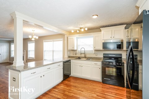 A kitchen with white cabinets and a black fridge.