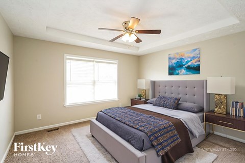A bedroom with a bed, a ceiling fan, and a painting on the wall.