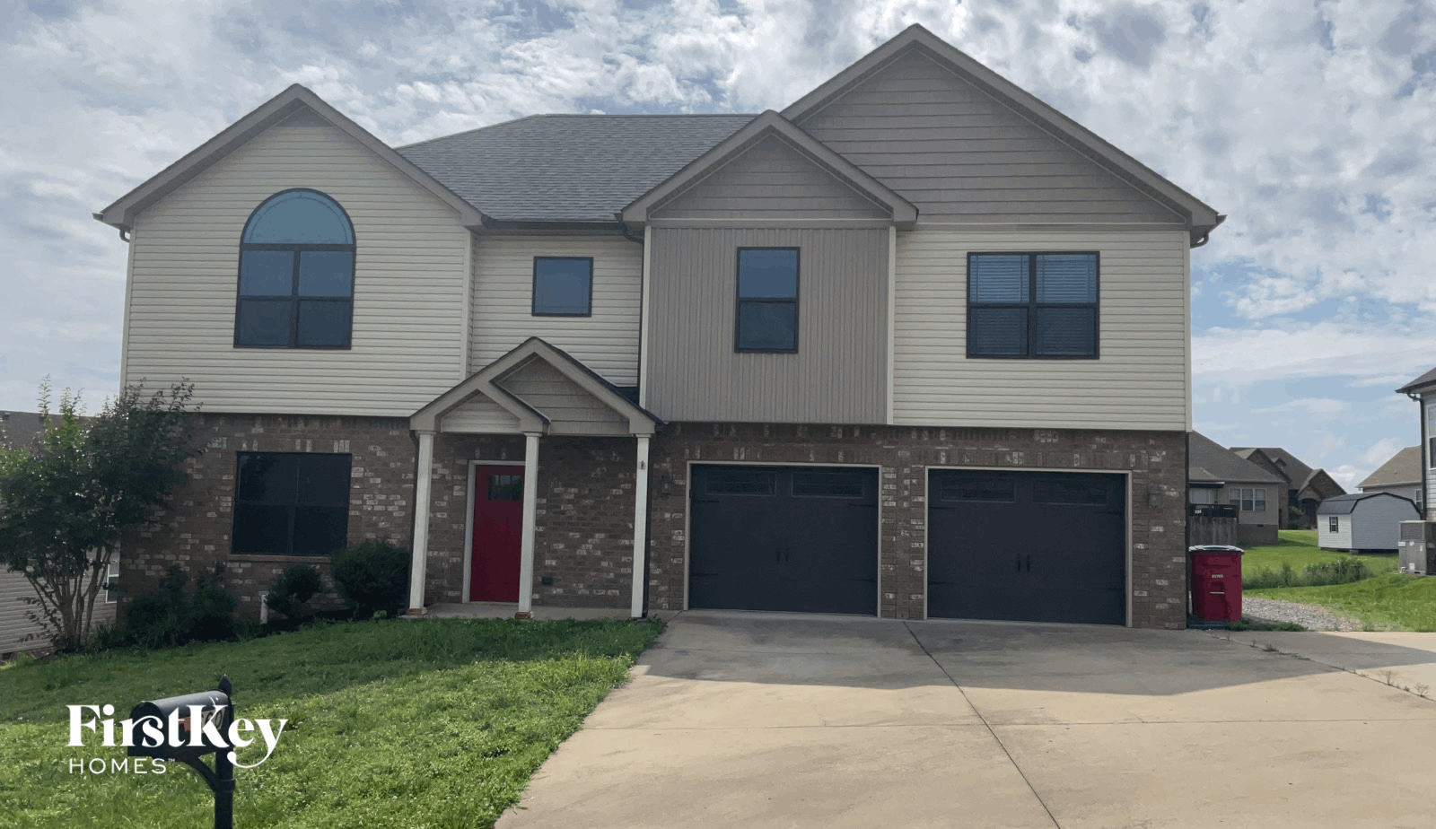 A two-story house with a red door and garage doors.