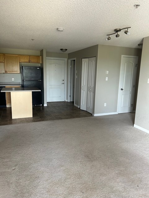 A kitchen with a black fridge and white cabinets.