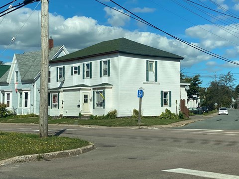 A white house with a blue sign in front of it.
