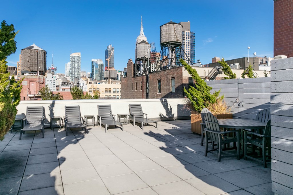 A rooftop patio with chairs and a table overlooking a city skyline.
