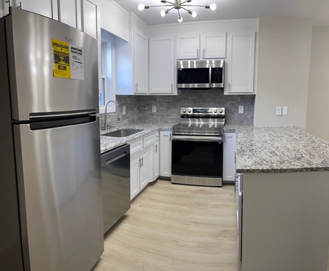 A kitchen with a stainless steel refrigerator and a stove top oven.