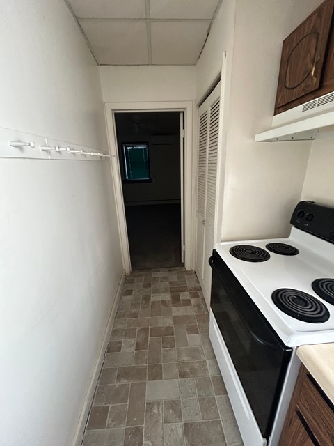 A kitchen with a white stove top oven and a tiled floor.