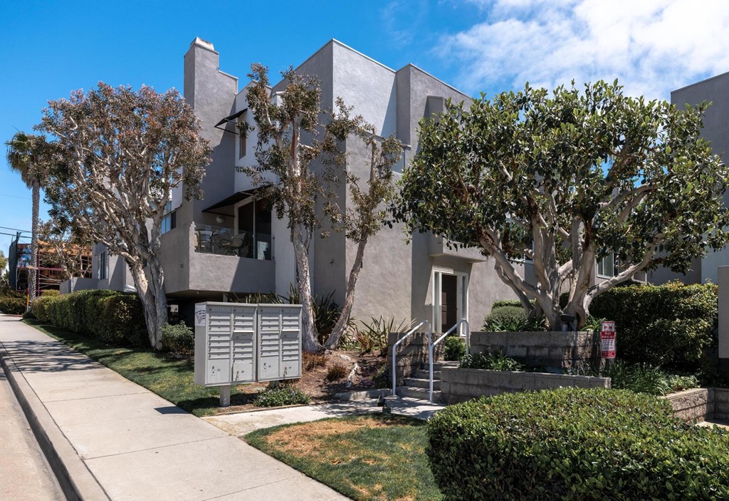 A modern house with a grey exterior and a tree in front.