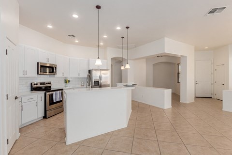 A kitchen with white cabinets and a white island.