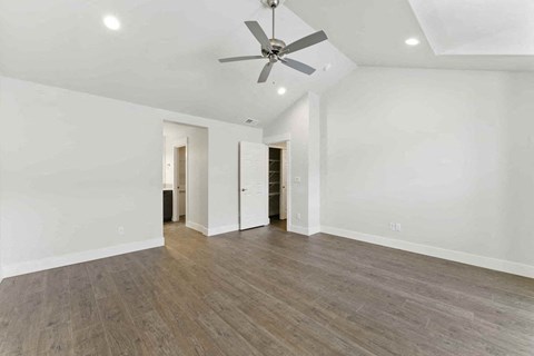 A spacious room with a ceiling fan and wooden flooring.