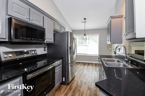 A kitchen with a black counter top and stainless steel appliances.