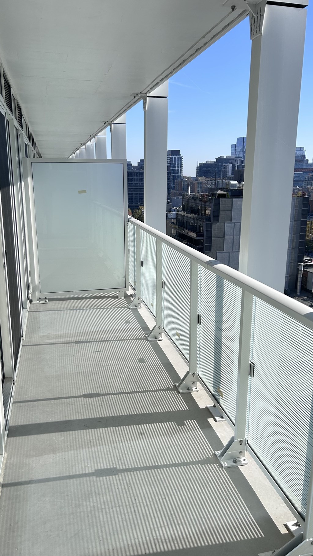 A long white bridge with a metal railing and glass panels.