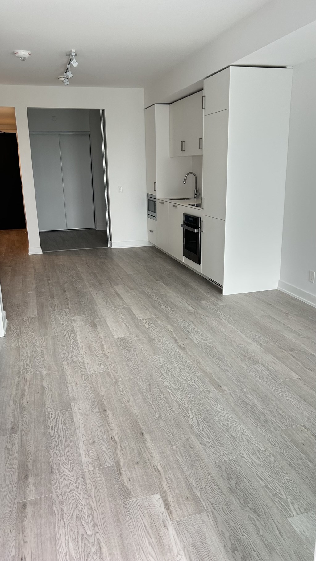 A kitchen with a white refrigerator and wooden flooring.