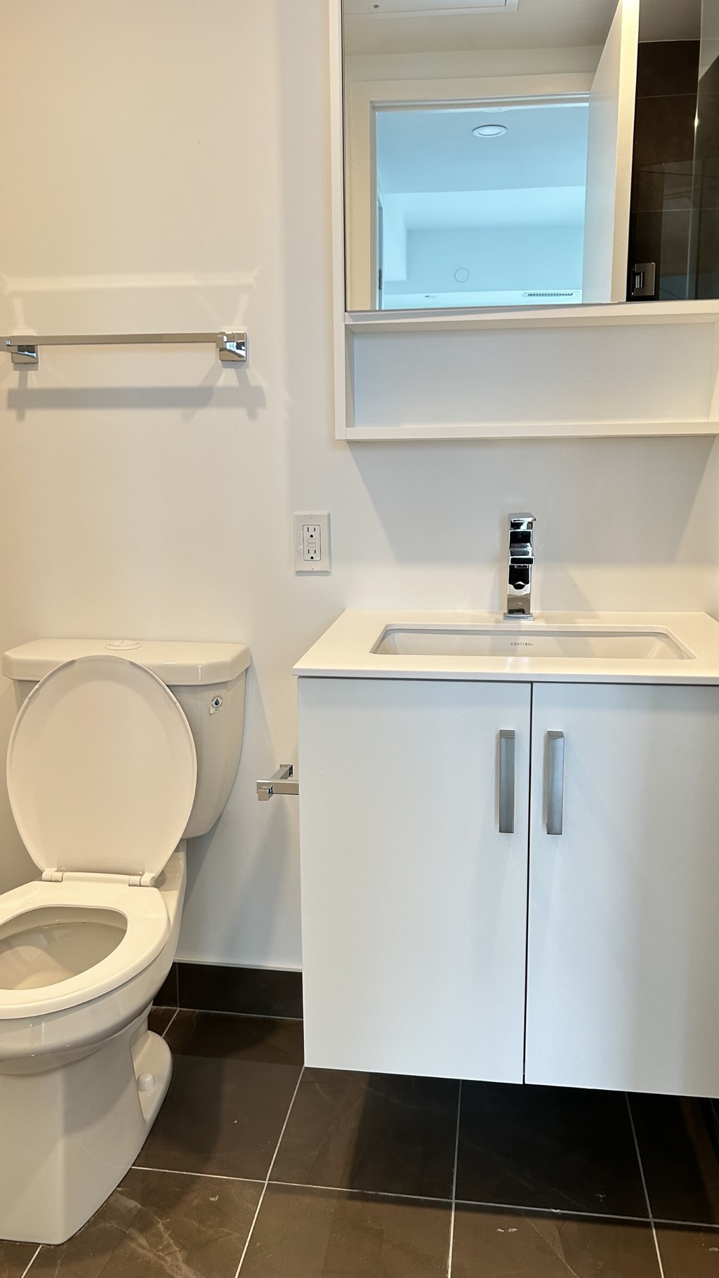 A white toilet and sink in a small bathroom.