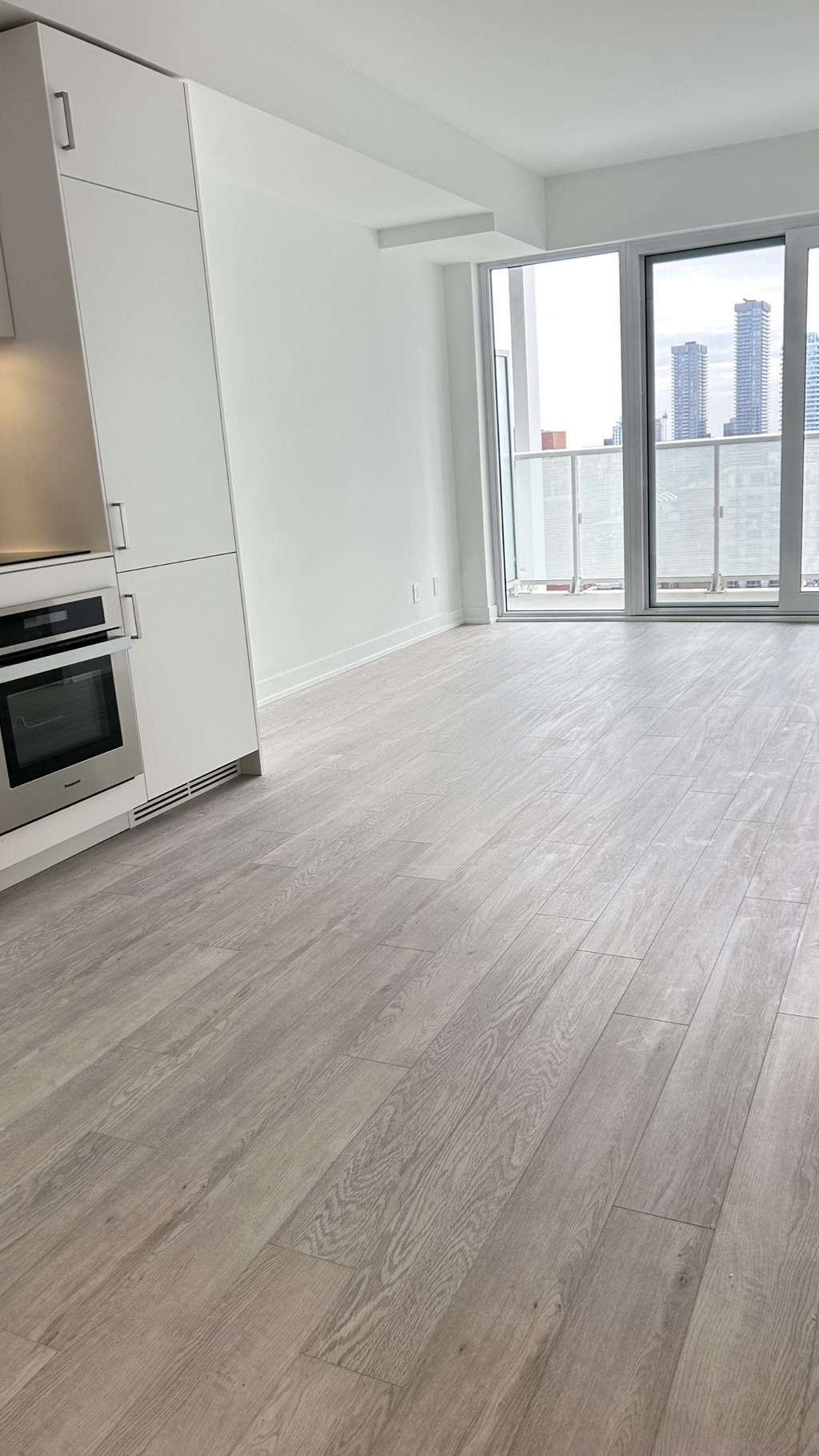 A kitchen with a stove top oven and a sliding glass door leading to a balcony.