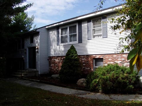 A house with a grey siding and a brick chimney.