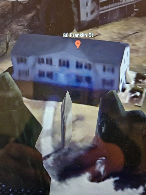 A person is holding a knife in front of a building with a sign that reads 86 Franklin St.