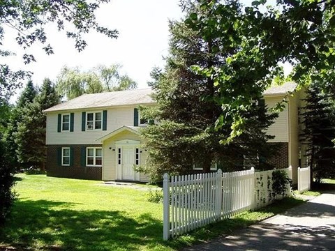 A white picket fence surrounds a two-story house.