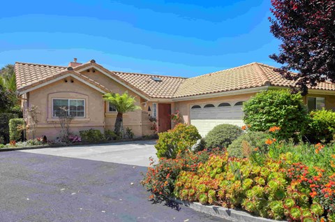 A house with a red tile roof and a driveway in front.