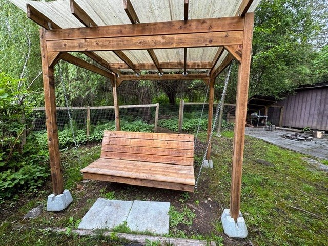 A wooden bench under a wooden pergola in a garden.