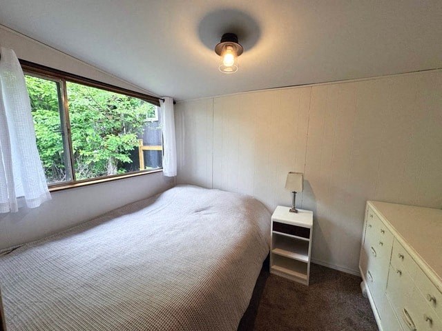 A bedroom with a bed, nightstand, and window.