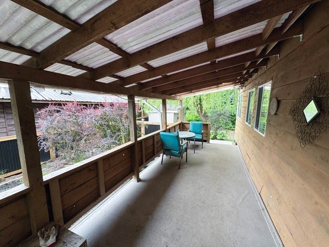 A wooden porch with a white ceiling and a table and chairs.