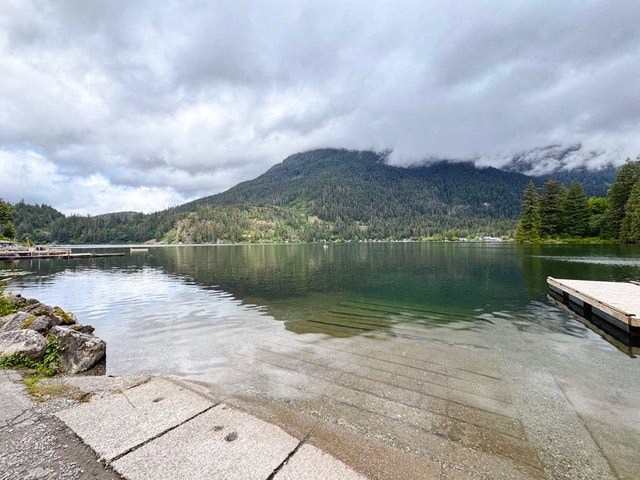 A serene lake with a dock and mountains in the distance.
