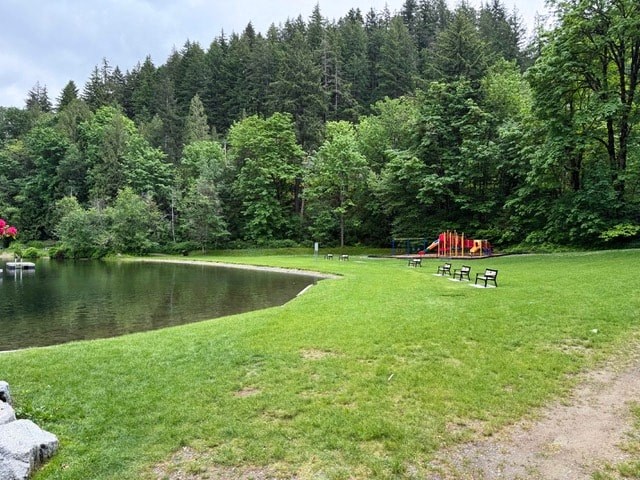 A playground with a slide is in the middle of a grassy area.