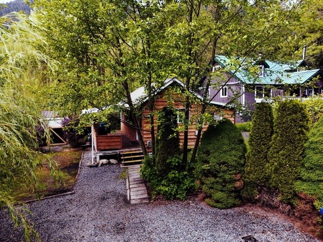 A gravel path leads to a wooden building surrounded by greenery.