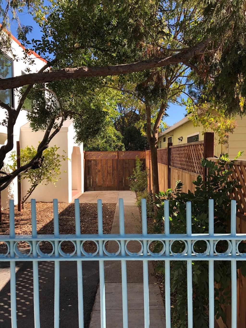 A blue gate leads to a house with a brown fence.