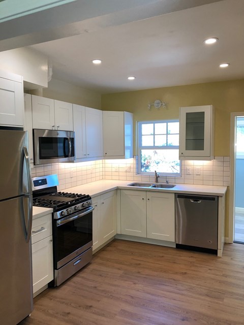 A kitchen with a stove, oven, refrigerator, and sink.
