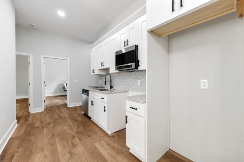 A kitchen with white cabinets and a black microwave.