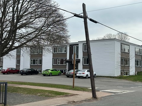 A street view of a residential area with cars parked in front of houses.